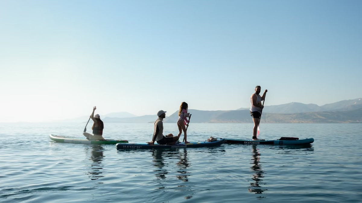 A family enjoys paddleboarding on a serene lake during a sunny day. Scenic outdoor activity captured beautifully.